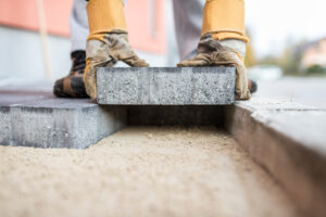 Two hands laying a brick in a foundation.